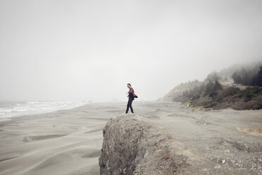 Seitenansicht eines Mannes, der bei nebligem Wetter auf einer Klippe am Strand steht - CAVF16872