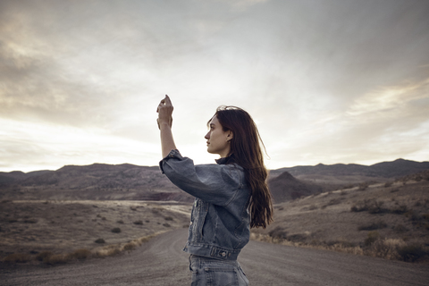 Frau fotografiert einen Berg, während sie auf einem Feld steht, lizenzfreies Stockfoto