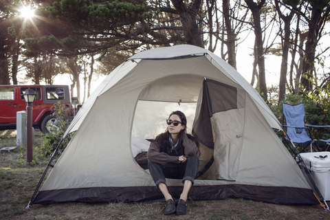 Frau mit Sonnenbrille entspannt im Zelt, lizenzfreies Stockfoto