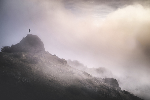 Einsamkeit Mann stehend auf Berg bei nebligem Wetter, lizenzfreies Stockfoto