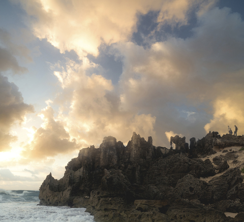 Malerischer Blick auf Felsformationen am Meer gegen den bewölkten Himmel bei Sonnenuntergang, lizenzfreies Stockfoto