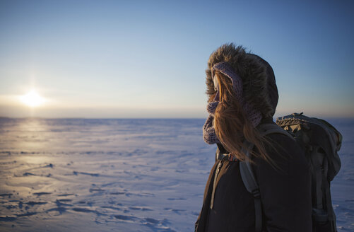 Side view of woman standing on snow covered landscape against sky - CAVF16985