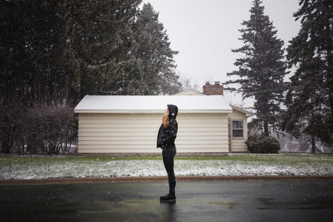 Side view of woman standing on street while snowing stock photo