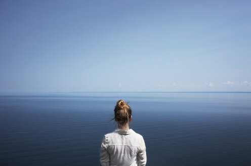 Rückansicht einer Frau, die vor dem Meer und dem Himmel steht - CAVF16992