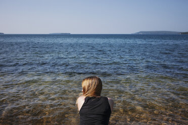 Rear view of woman against sea on sunny day - CAVF16994