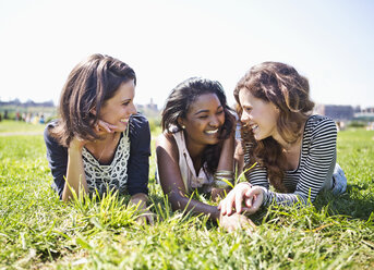 Friends relaxing on grassy field against sky - CAVF17087