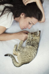 Hohe Winkel Ansicht der Frau mit Katze auf dem Bett liegend zu Hause - CAVF17117