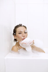 Portrait of woman blowing foam while bathing at home - CAVF17130