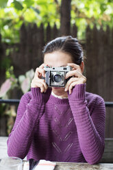 Frau beim Fotografieren im Restaurant sitzend - CAVF17143