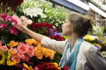 Frau prüft Blumen an einem Marktstand - CAVF17148