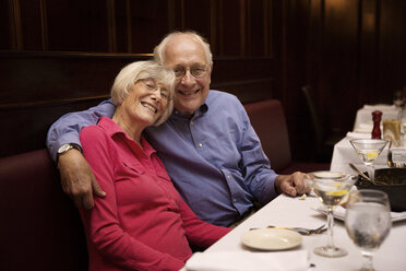 Porträt eines älteren Paares, das in einem Restaurant sitzt und den Arm um sich legt - CAVF17185