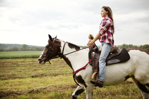 Seitenansicht von Cowgirls, die auf einem Pferd reiten - CAVF17202