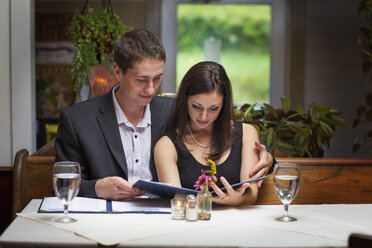 Ehepaar liest Speisekarte im Restaurant - CAVF17224