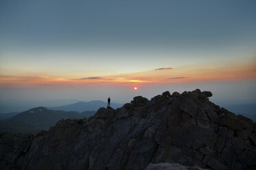 Fernblick auf einen Mann, der bei Sonnenuntergang auf einem Berg steht - CAVF17250