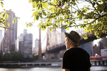 Rear view of man standing by against Queensboro Bridge and buildings - CAVF17271