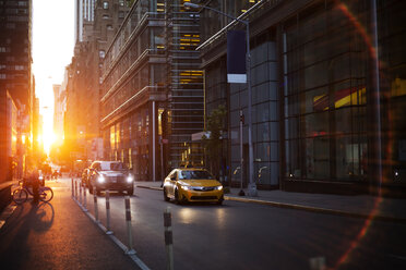 Fahrzeuge auf der Straße inmitten moderner Gebäude bei Sonnenuntergang - CAVF17273
