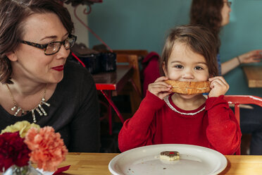 Mutter beobachtet Tochter beim Brotessen am Restauranttisch - CAVF17289