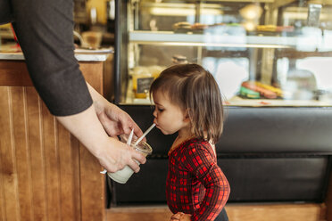 Mutter füttert ihre Tochter im Restaurant mit Milch - CAVF17290