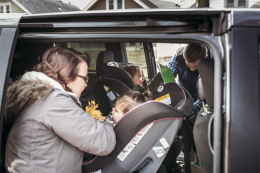 Eltern stellen Mädchen auf Autositze ein - CAVF17293