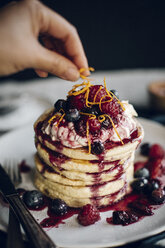 Cropped image of hand garnishing pancakes with orange peels - CAVF17299