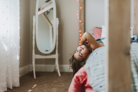 Porträt eines Mädchens, das zu Hause auf dem Bett liegt, lizenzfreies Stockfoto