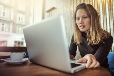 Junge Frau mit Laptop am Kaffeetisch - CAVF17323