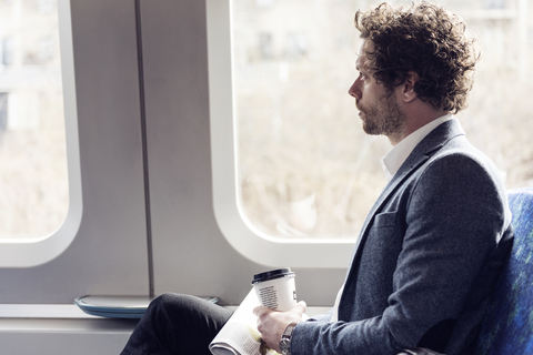 Seitenansicht eines Geschäftsmannes, der durch ein Zugfenster schaut, lizenzfreies Stockfoto
