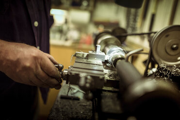 Midsection of man operating machinery in workshop - CAVF17344