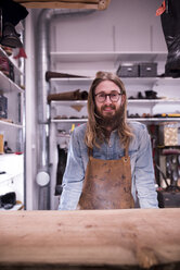 Portrait of smiling shoemaker standing in workshop - CAVF17353