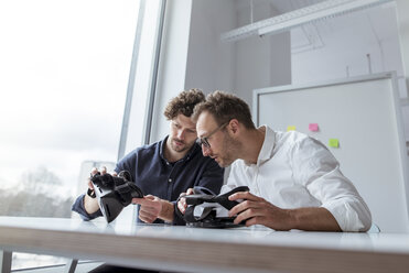 Engineers examining virtual reality simulators at table in office - CAVF17375