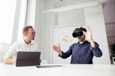 Ingenieur mit Tablet-Computer, der einen Mitarbeiter bei der Untersuchung eines Virtual-Reality-Simulators im Büro beobachtet - CAVF17392