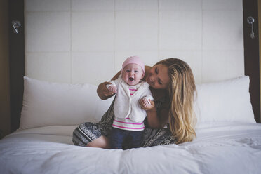Mutter, die ihrem Baby hilft, sich zu Hause auf das Bett zu stellen - CAVF17432