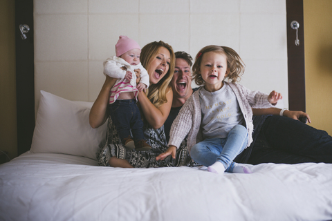 Glückliche Eltern mit Töchtern im Bett zu Hause, lizenzfreies Stockfoto