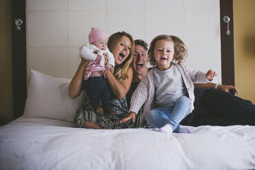Glückliche Eltern mit Töchtern im Bett zu Hause - CAVF17435