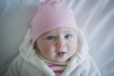 Porträt eines Babys in warmer Kleidung auf einem Bett zu Hause liegend - CAVF17436