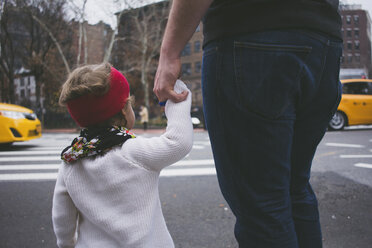 Vater und Tochter halten sich beim Überqueren der Straße an den Händen - CAVF17438