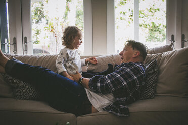 Playful family enjoying on sofa at home - CAVF17440