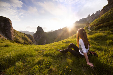 Woman sitting on mountain against sky - CAVF17468