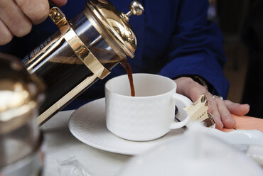 Ausgeschnittenes Bild von Händen, die Kaffee in eine Tasse gießen - CAVF17516