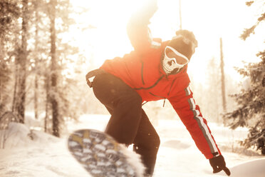 Mann beim Snowboarden auf verschneitem Feld - CAVF17590