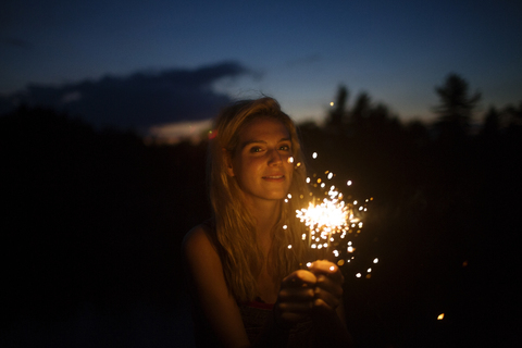 Porträt einer lächelnden Frau mit Wunderkerzen bei Nacht, lizenzfreies Stockfoto