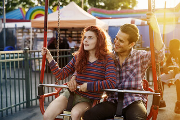 Young couple enjoying ride at amusement park - CAVF17678