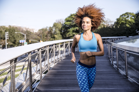 Woman jogging on bridge against sky stock photo