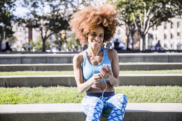 Porträt einer Frau, die im Park ein Mobiltelefon benutzt - CAVF17705