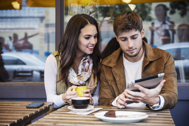 Couple using tablet computer while sitting at cafe - CAVF17731