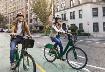 Glückliches Paar beim Fahrradfahren auf einer Stadtstraße - CAVF17748