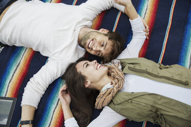 High angle view of loving couple looking at each other while lying on blanket - CAVF17764