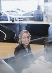 Porträt einer lächelnden Autoverkäuferin im Ausstellungsraum eines Autohauses - CAIF20032