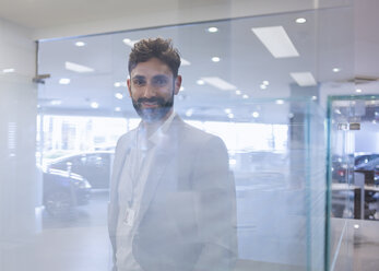 Portrait smiling, confident car salesman in car dealership showroom - CAIF20062