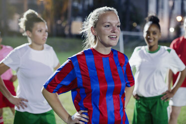 Selbstbewusste junge Fußballspielerinnen, die sich nachts auf dem Spielfeld mit den Händen in den Hüften ausruhen - CAIF20105